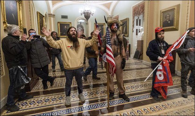 Supporters of President Donald Trump are confronted by U.S. Capitol Police officers outside the Senate Chamber inside the Capitol in Washington Wednesday. At center is Jake Angeli, wearing fur hat with horns, a regular at pro-Trump events and a known follower of QAnon.